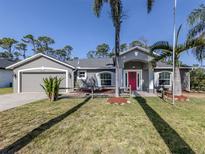 Charming single-story home with a gray exterior, well-manicured lawn, and vibrant pink front door at 3255 Tally Ho Rd # 1, North Port, FL 34291