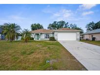 Charming single-story home with a well-maintained lawn, palm trees, and a two-car garage at 3870 Log Cabin Rd, North Port, FL 34291