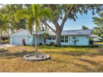 Charming single-story home with a light blue exterior, a palm tree, and mature trees offering ample shade at 421 Blackburn Rd, Nokomis, FL 34275