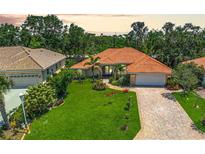 Charming single-story home boasting lush landscaping, brick driveway, and a vibrant orange tile roof at 4856 Jacaranda Heights Dr, Venice, FL 34293