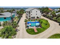 An aerial view of a home's backyard, featuring a private pool with lounge chairs and a grassy area with palm trees at 5031 N Beach Rd # 118, Englewood, FL 34223