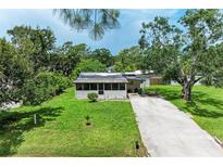 Charming single-story home with a long concrete driveway and lush green lawn at 5106 S Lockwood Ridge Rd, Sarasota, FL 34231