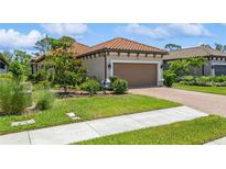 Charming home featuring a tile roof, well-manicured landscaping, and a brown two-car garage at 5856 Semolino St, Nokomis, FL 34275