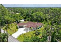 An aerial view of a home with a red roof surrounded by trees at 66 Statler St, Port Charlotte, FL 33954