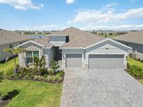 Aerial view of the home showing the three car garage, landscaping, and paver driveway at 8529 Saint Kitts Cir, Englewood, FL 34224