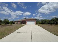 Charming single-story home featuring a long driveway, two-car garage, and a well-maintained front yard at 98 Maltby St, Port Charlotte, FL 33953