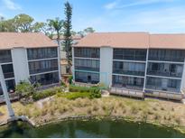 Condo Building with screened lanais overlooks lush landscaping and pond at 1156 Bird Bay Way # 104, Venice, FL 34285