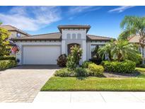 Charming single-story home featuring a tile roof, brick driveway, and lush tropical landscaping at 19337 Cruise Dr, Venice, FL 34292