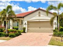 Charming single-story home with a red tile roof, two-car garage, and lush tropical landscaping at 236 Soliera St, Nokomis, FL 34275