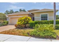 Inviting single-story home with a well-manicured lawn and a paver driveway leading to the attached two-car garage at 24849 Pennington Ter, Venice, FL 34293