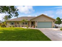Charming single-story home with a well-manicured lawn, blue shutters and a two-car garage at 30 Jamestown Ave, Englewood, FL 34223