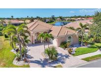 Beautiful single-Gathering home with a tile roof, arched entryway, palm trees, and brick driveway at 4403 Via Del Villetti Dr, Venice, FL 34293