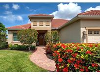 Charming home featuring a brick walkway leading to the front door with beautiful landscaping and a clay tile roof at 515 Sawgrass Bridge Rd, Venice, FL 34292