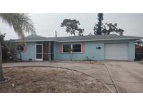 Charming one-story home featuring a light blue exterior, pink shutters and a circular driveway at 1001 Sandlewood Dr, Venice, FL 34293