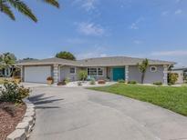 Charming single-story home boasts a well-manicured lawn, elegant landscaping, and a stylish turquoise double-door entrance at 1234 Paradise Way, Venice, FL 34285