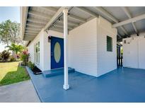 Inviting blue front door and covered porch welcome you to this charming home at 140 Poinsettia Ne Cir, Port Charlotte, FL 33952
