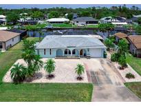 Charming waterfront home with a light blue exterior and well-maintained landscaping at 18302 Burkholder Cir, Port Charlotte, FL 33948