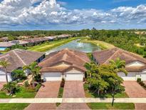 Beautiful aerial view of homes and a pond with a fountain on a sunny day with trees and blue skies at 20636 Swallowtail Ct, Venice, FL 34293