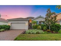 Charming single-Gathering home featuring a brick driveway, attached garage, and beautiful lawn with lovely landscaping at 2150 Snapdragon Ln, Venice, FL 34292