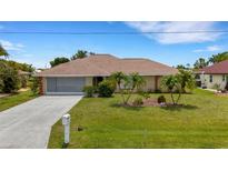 Charming single-story home featuring a well-manicured lawn, mature landscaping, and screened garage at 25509 Arequipa Dr, Punta Gorda, FL 33983