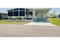 Charming home featuring a covered carport, front porch with an enclosed sunroom, and manicured landscaping at 304 Roma Rd, Venice, FL 34285