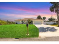 Charming single-story home featuring a manicured lawn and a pristine driveway leading to an attached two-car garage at 381 La Playa Ln, Port Charlotte, FL 33953
