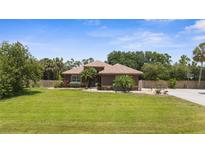 Charming single-story home boasts a well-manicured lawn and tropical landscaping at 3950 Pepper Ln, North Port, FL 34287