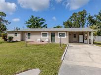 Single-story home featuring a well-maintained lawn, carport, and a small patio with chairs at 4192 Tarpon Rd, Venice, FL 34293
