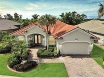 Charming single-story home featuring a red tile roof, mature landscaping, and a paved driveway and walkway at 4912 Bella Terra Dr, Venice, FL 34293
