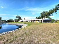 Scenic view of homes situated on a lush green lawn with a tranquil pond at 57 Sandstone Cir, Venice, FL 34293