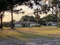 Lovely single-story home with neutral tones surrounded by luscious landscaping and stately palm trees at 5760 Howard Creek Rd, Sarasota, FL 34241