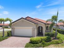 Charming single-story home featuring a red tile roof, lush landscaping, and a brick driveway at 10209 Fiddlewood Dr, Venice, FL 34293