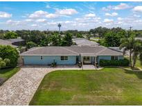 Charming light blue home features a well-manicured lawn, a brick driveway, and a cozy pergola-covered seating area at 1099 Nokomis S Ave, Venice, FL 34285