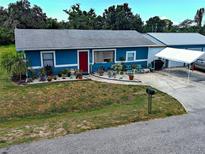 Charming blue single-story home with red front door and well-kept lawn with garage and boat parking at 1103 Lucille Ave, Nokomis, FL 34275