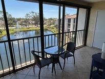Enclosed balcony features a glass table and chairs with serene views of the community lake and fountain at 1154 Bird Bay Way # 303, Venice, FL 34285