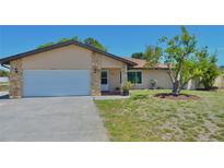 Charming single-story home with a two-car garage, beige exterior, and well-manicured lawn at 1203 Hudson Rd, Venice, FL 34293