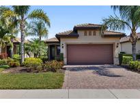 Charming home features a two-car garage, tile roof, lush landscaping, and a brick paver driveway at 13829 Alafaya St, Venice, FL 34293