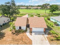 Inviting home featuring a well-maintained lawn, and a golf course view with mature trees in the background at 1439 Strada D Argento, Venice, FL 34292