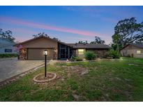 Charming single-story brick home with a well-manicured lawn and inviting curb appeal at twilight at 1515 Pecan St, Nokomis, FL 34275