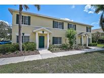 Well-maintained, two-story townhouse featuring a green door, dark shutters, and lush landscaping at 233 Cape Harbour Loop # 107, Bradenton, FL 34212