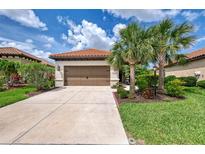 Charming single-story home with a two-car garage, terracotta roof, and mature landscaping at 241 Marcheno Way, Nokomis, FL 34275