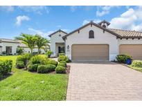 Charming home featuring a two-car garage, landscaped front yard with brick paved driveway, and lush greenery at 27467 Janzen Ct, Englewood, FL 34223