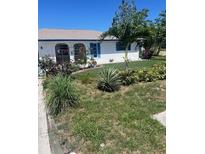 Charming single-story home featuring a lush front yard with a mix of flowers, plants, and a vibrant green lawn at 3031 Englewood Rd, Venice, FL 34293