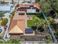 Aerial view of a home showing a large backyard with a fire pit, putting green and a covered patio with outdoor seating at 409 Armada S Rd, Venice, FL 34285