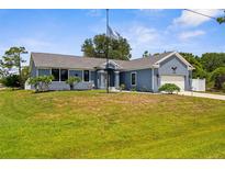 Charming blue single-story home featuring a well-manicured lawn and attached two-car garage at 4305 Heyward St, North Port, FL 34291