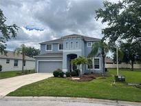 Two-story home featuring a well-manicured lawn, landscaping, attached garage, and covered entrance at 5966 Willows Bridge Loop, Ellenton, FL 34222