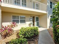 Inviting condo entrance featuring manicured landscaping and a charming second-story balcony at 821 Waterside Dr # 106, Venice, FL 34285