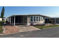 Well-maintained single-story home with a brick-lined driveway, lush lawn, and an inviting, covered porch at 902 Jolanda Cir, Venice, FL 34285