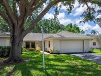 Charming single-story home with a well-manicured lawn, mature tree and a two-car garage at 114 Southampton N Pl # 237, Venice, FL 34293