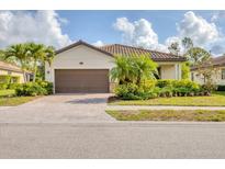 Charming single-story home with a well-manicured lawn, mature landscaping, and a brown tile roof at 12370 Canavese Ln, Venice, FL 34293